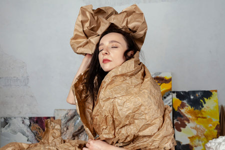 Portrait of a creative young woman wrapped in kraft paper in her creative studio.の写真素材