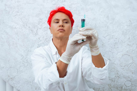 Woman with a short bright red hair in a white room holding needle. Drug addiction concept.の写真素材