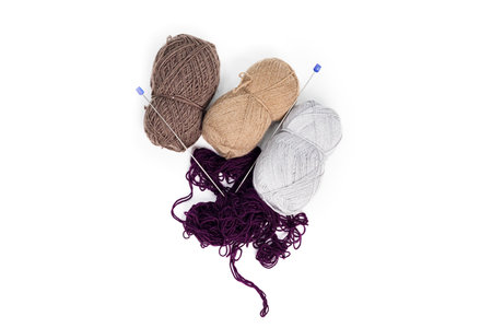 Brown, beige, white, and purple yarns with knitting needles are lying on a white isolated background. Copy space.の写真素材
