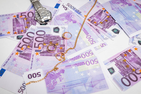 Bunch of 500 euro Banknotes, watches and golden accessories, rings and chains lying on a isolated...