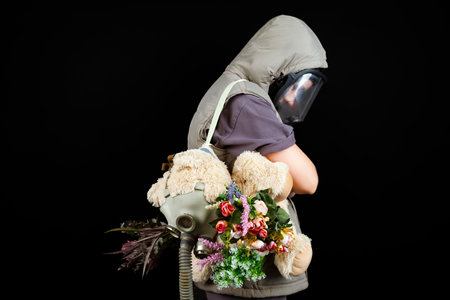 A portrait of a lonely sad girl and a plush toy wearing gas masks, on an isolated black background. Concept of loneliness, nature and air pollution.の写真素材