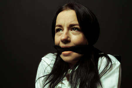 A mentally unstable and ill woman in a straitjacket with a cloth tied over her mouth in a...