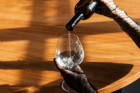 Close-up of hands in Mesh Sheer gloves of an elegant girl pouring a water into a glass. Concept of elegance and sophistication.の写真素材