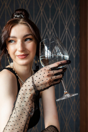 Beautiful, gorgeous and elegant girl in a black dress and Mesh Sheer gloves on her hands, sitting at...