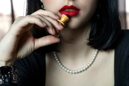 Close-up of a  beautiful and elegant girl's lips with bright matte red lipstick and a chess piece.の写真素材
