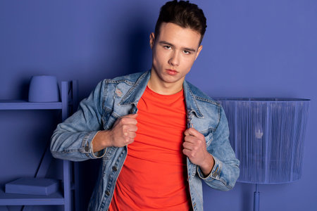 Portrait of a handsome young man in denim clothes posing in a room where everything is blue or purple, a room that is completely painted in one color. Brutal guy.の写真素材