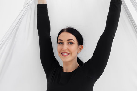 Female in black tights. Professional aerial performer. Inverted anti-gravity Aerial yoga with the use of aerial silks or fabrics, Balance between physical and mental effort concept. Isolated on white.の写真素材
