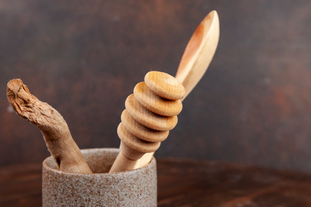 Vase or bowl with wooden spoons and honey dipper on a wooden table.の写真素材