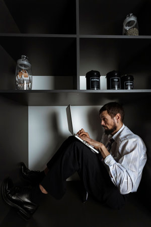 A Businessman or office worker, employee sitting and working in a very small space.Fear of enclosed spaces. Little personal space.の写真素材