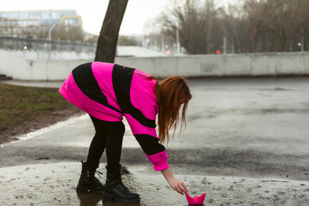 Woman in bright purple sweater plays with origami. Rainy day, rejoice of lifeの写真素材