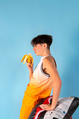 Funny man with blue inflatable swimming circle flaunts his strength on light blue background. Full length of playful strong male swimmer. Summer vacation concept.の写真素材