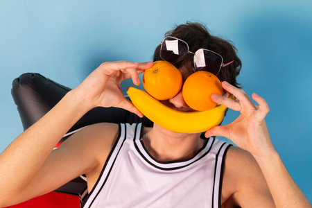 Funny man with blue inflatable swimming circle flaunts his strength on light blue background. Full length of playful strong male swimmer. Summer vacation concept.の写真素材
