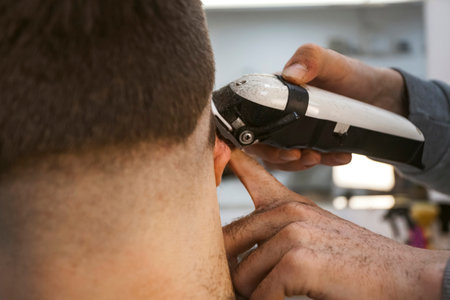 A hairdresser or barber is working with a shaving machine on the hair. bends the earの写真素材