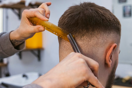 A hairdresser or barber is working on the hair at the back of a client's head using scissors and a comb.の写真素材