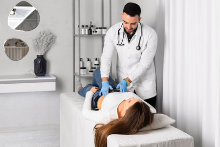 Doctor in clean or sterile gloves is performing a medical examination of the female patient by pressing on her abdomen.の写真素材