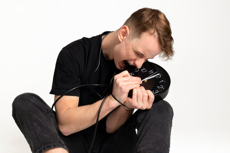 A young man addicted to modern gadgets and technology. Using his gadgets without noticing the surrounding world. Device dependency. Technological immersion. Isolated on white background.の写真素材
