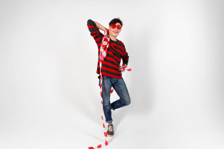 A young guy in a red and black clothes and heart shaped glasses tied with a caution or barrier tape. Isolated on white background. copy space.の写真素材