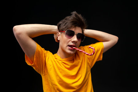 A young guy addicted to sweets, candies and sugar. Isolated on black background. copy space.の写真素材