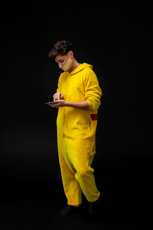 A young guy in a yellow pajama with a taped mouth. freedom of speech issues concept.