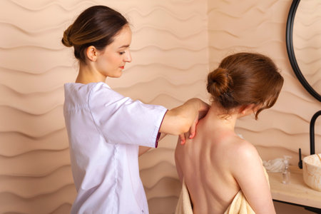 A masseuse or massage therapist is massaging girl's back. Concept of relaxation and self-care.の写真素材