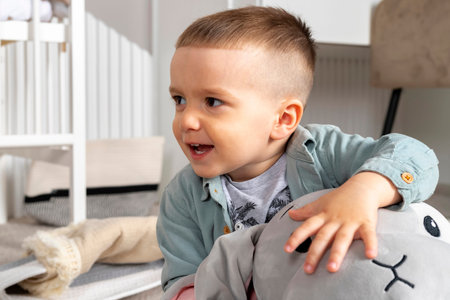 Little baby boy playing with soft plush toys and smiling, laughing.