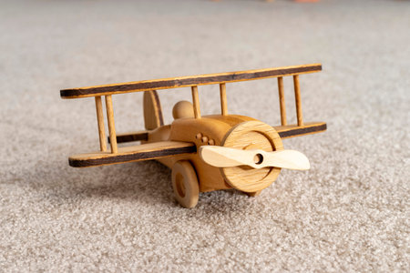 Close-up of a wooden airplane toy lies on a carpet.