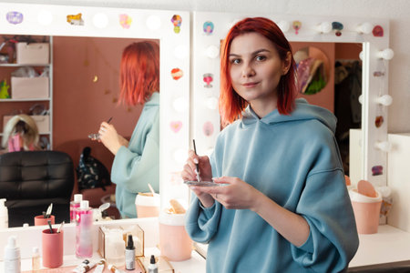 makeup artist or visagiste mixing paint on a small glass palette.の写真素材