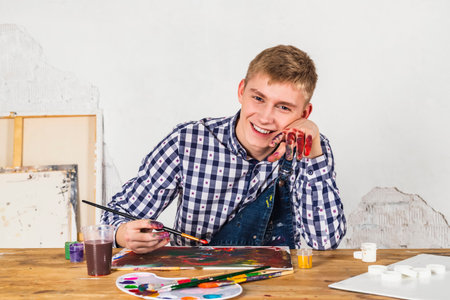 happy smiling painter or artist In checkered shirt working on a new art in a workshop.の写真素材