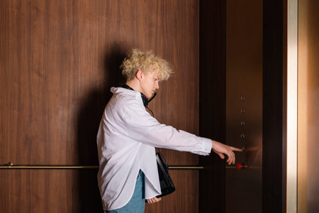 Young trendy teenager, the programmer or IT specialist with a laptop or notebook in hand is pressing...
