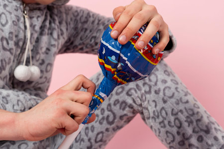 A curly blond guy in a cute and funny gray spotted animal pajamas pretends to be a kid, holding a...