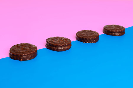 Delicious chocolate cookies on a purple and blue geometric two color soft paper pastel background.の写真素材