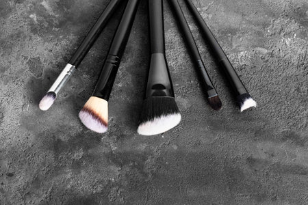 Set of makeup brushes, cosmetics, makeup tools on a dark gray spotted background. flat lay, top...