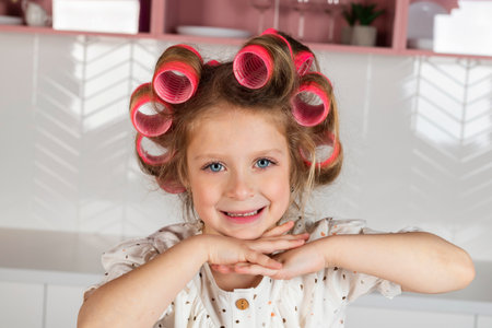 Portrait of a charming little girl wearing hair rollers and white polka dot dress. Happy Child with a big blue eyes posing and looking at the camera.の写真素材