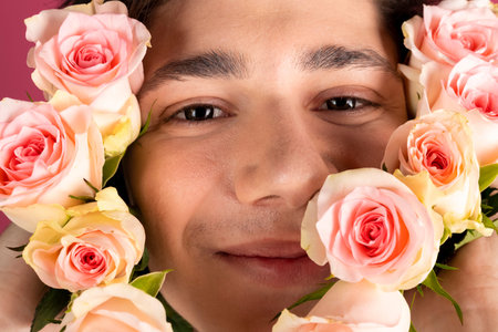 Close-up portrait of a romantic handsome young man surrounded with flowers or roses.の写真素材