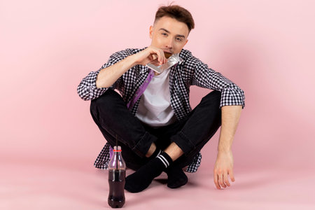 A happy young man drinking coke and eating a chocolate bar. fast food and sugar addiction, unhealthy...