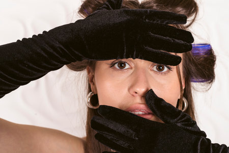 Portrait of A beautiful girl in a corset and elbow length gloves with hair in curlers, getting ready for an elegant evening meeting or party.の写真素材