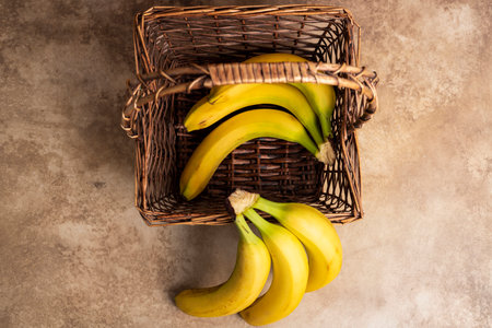 Bunch of bananas in a wicker basket against a wooden background. top view, flat lay, copy space.の写真素材