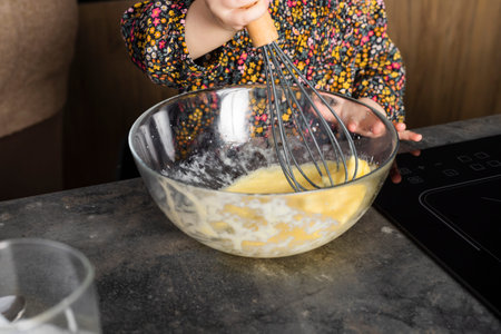 Little girl on a modern kitchen, helping her mother and having fun.