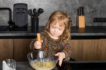 Little girl on a modern kitchen, helping her mother and having fun.