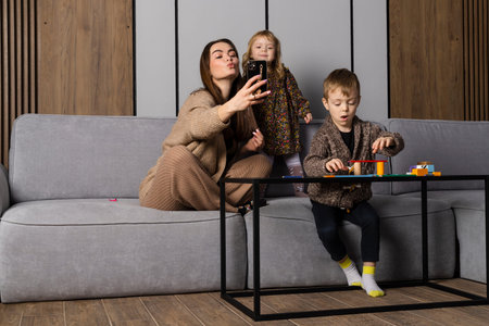 Mother or nanny taking picture of siblings that are playing and spending their time together,...