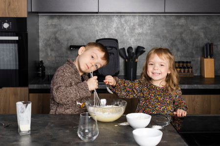 Little siblings cooking together on a modern kitchen, helping each other and having fun while mother is gone.の写真素材