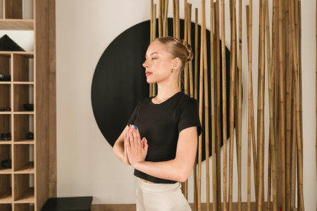 Young Slim blonde Girl practicing yoga, doing exercise, stretching and warming up, wearing sportswear, pants and top, indoor in a studio in Japanese style.の写真素材