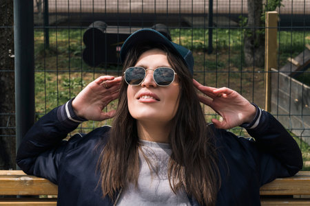 Happy smiling Young brunette girl in casual sport suit clothing and sunglasses outdoor on the...