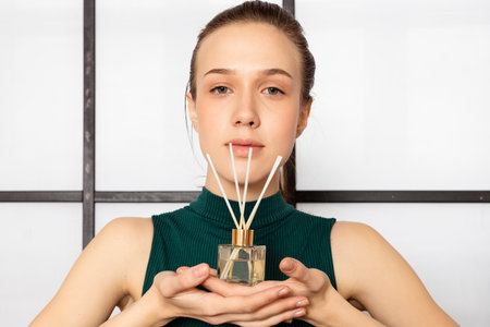 Tender Slim brunette Girl in dark green sleeveless top holds incense sticks against the white background.の写真素材