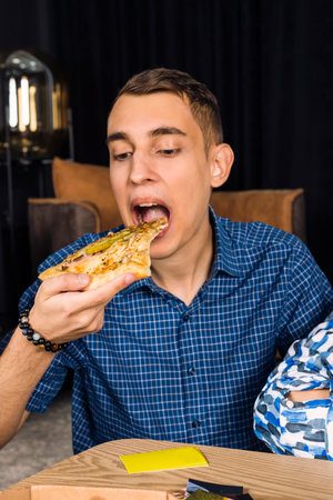 Happy young man biting a pizza slice.の写真素材