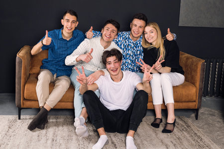 Group photo of a happy friends sitting on a couch in a living roon. small group of friends photo.の写真素材