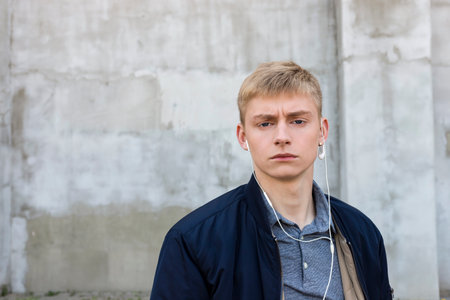 Serious looking Young blond man in casual clothes looking at the camera outdoors on the street.の写真素材
