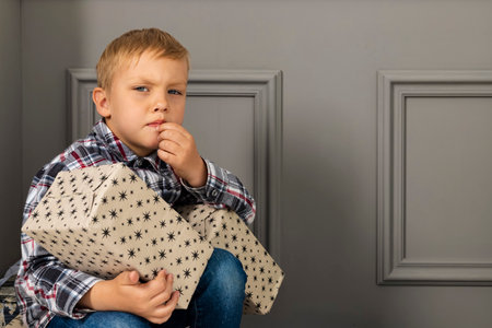 Thoughtful Little boy with the stack of presents. Child unwrapping gifts.の写真素材