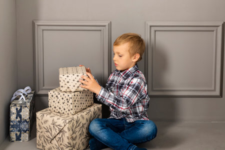 Little boy with the stack of presents. Child unwrapping gifts.の写真素材