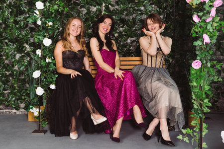Three beautiful girls in Elegant Exquisite Evening Dresses in front of floral decorations and plants.の写真素材